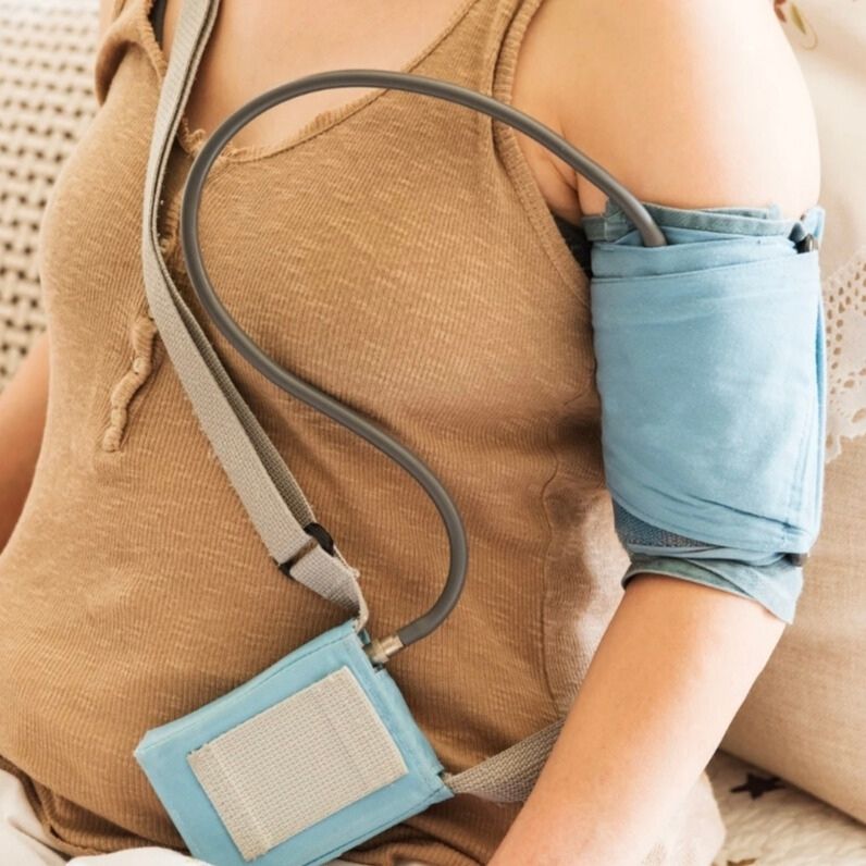 Person trägt ein tragbares 24h-EKG-Gerät zur Langzeitüberwachung der Herzaktivität, verbunden mit Elektroden auf der Brust.